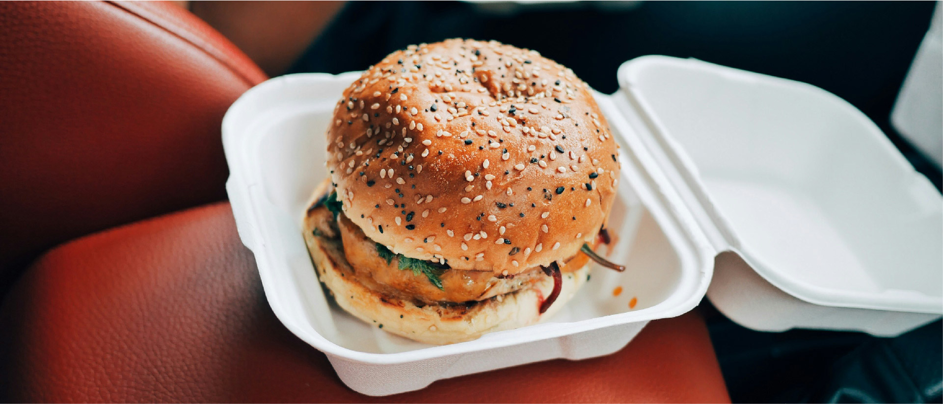 chicken sandwhich in a to go box inside of a car seat